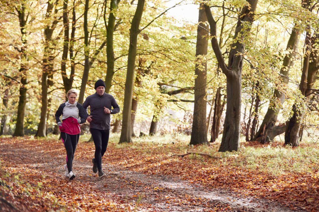 encouraging healthy eating Couple Running Through Autumn Woodland Together