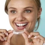 fees at Whitchurch shows Young woman holding Invisalign braces