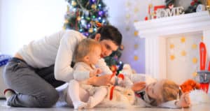 man and two daughters holiday opening parcels