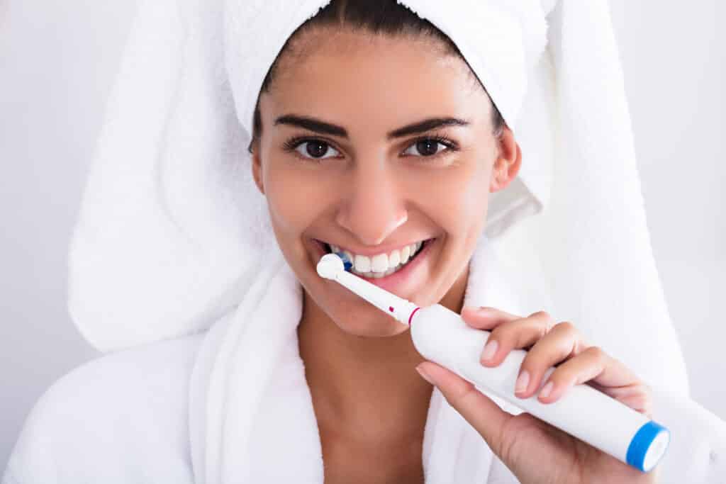woman cleaning teeth with electric (manual) toothbrush