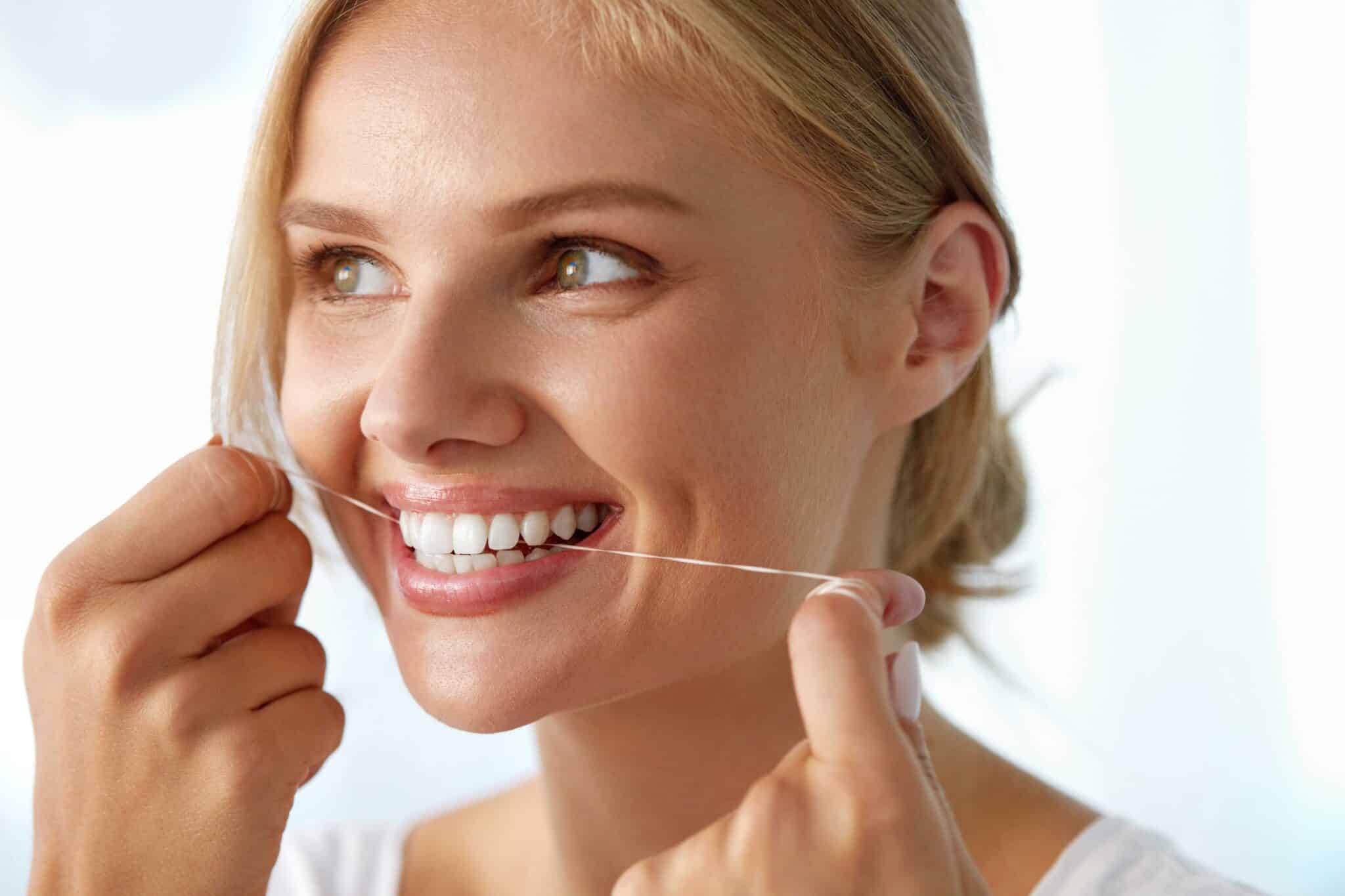 woman flossing helps teeth and gums correct hold.