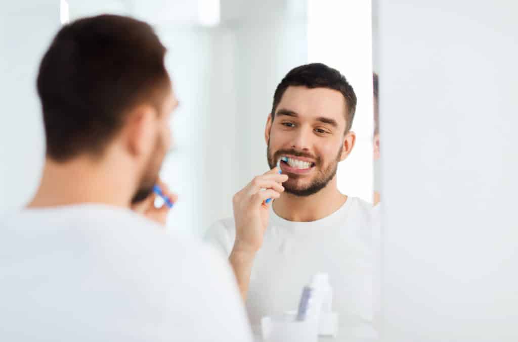 Man with tidy tooth brushing kit in a white bathroom