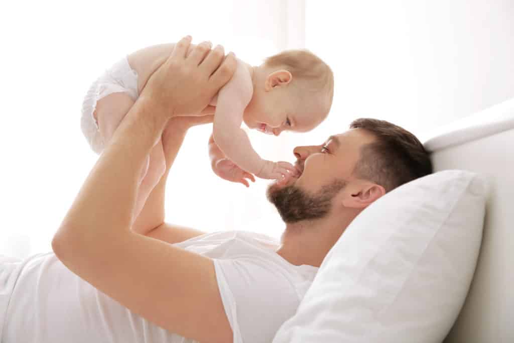 man holding baby for dental check by ne