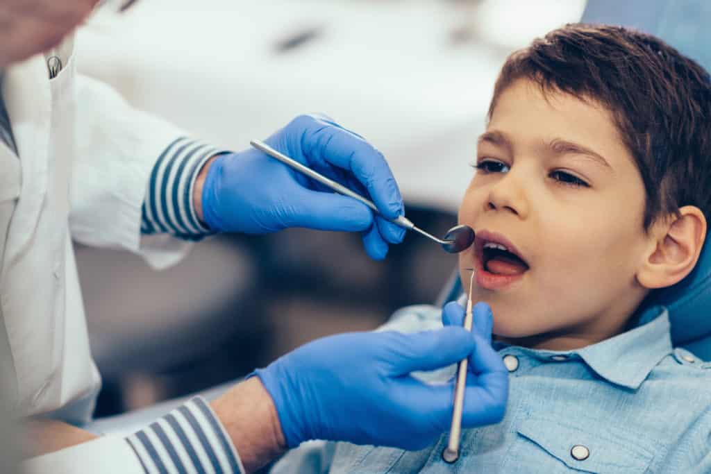 snesory processing by boy in chair wearing blue shirt at dentist